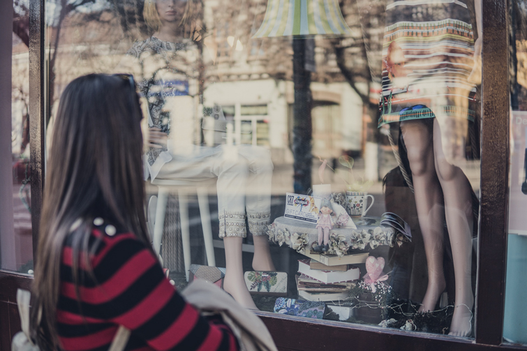 Frau, die ein Ladenfenster von einem Second Hand Kleidung in Kassel betrachtet