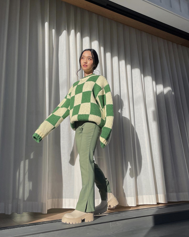 eine der wichtigste Influencerinnen: Jenn Im trägt ein stilvolles Outfit, bestehend aus einem grün karierten Pullover und einer grünen Hose