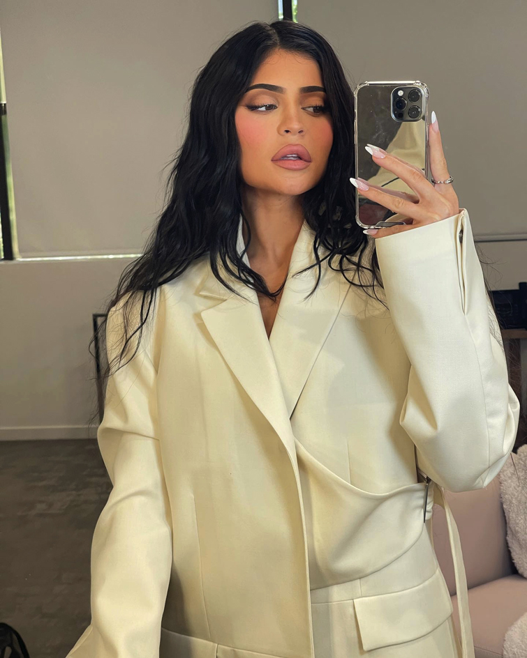 eine der wichtigste Influencerinnen der Welt: Kylie Jenner, die ein Selfie vor einem Spiegel macht. Sie ist mit einem gelben Blazer bekleidet 
