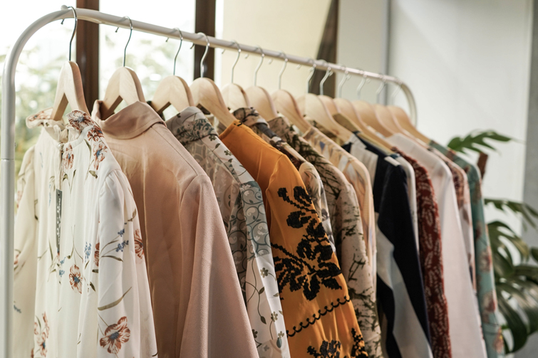 Ein Kleiderträger in einem Second Hand in Nürnberg Ankauf Kleidung der mehrere bunte Hemden zum Verkauf anbietet