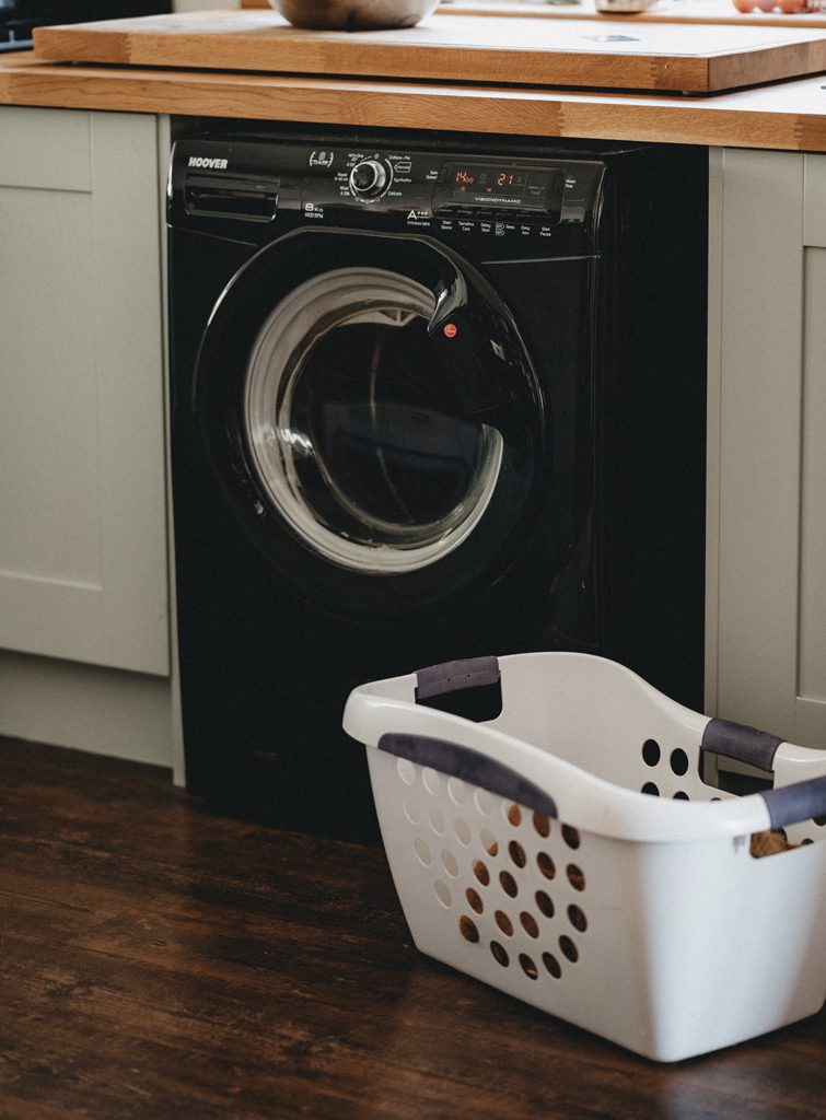 schwarze Waschmaschine in einer Küche mit einem Korb für Wäsche
