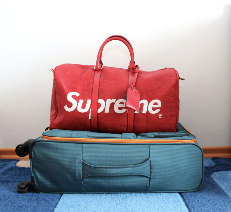 blauer Koffer und rote Reisetasche der Marke Louis Vuitton und Urban Kleidung Supreme 