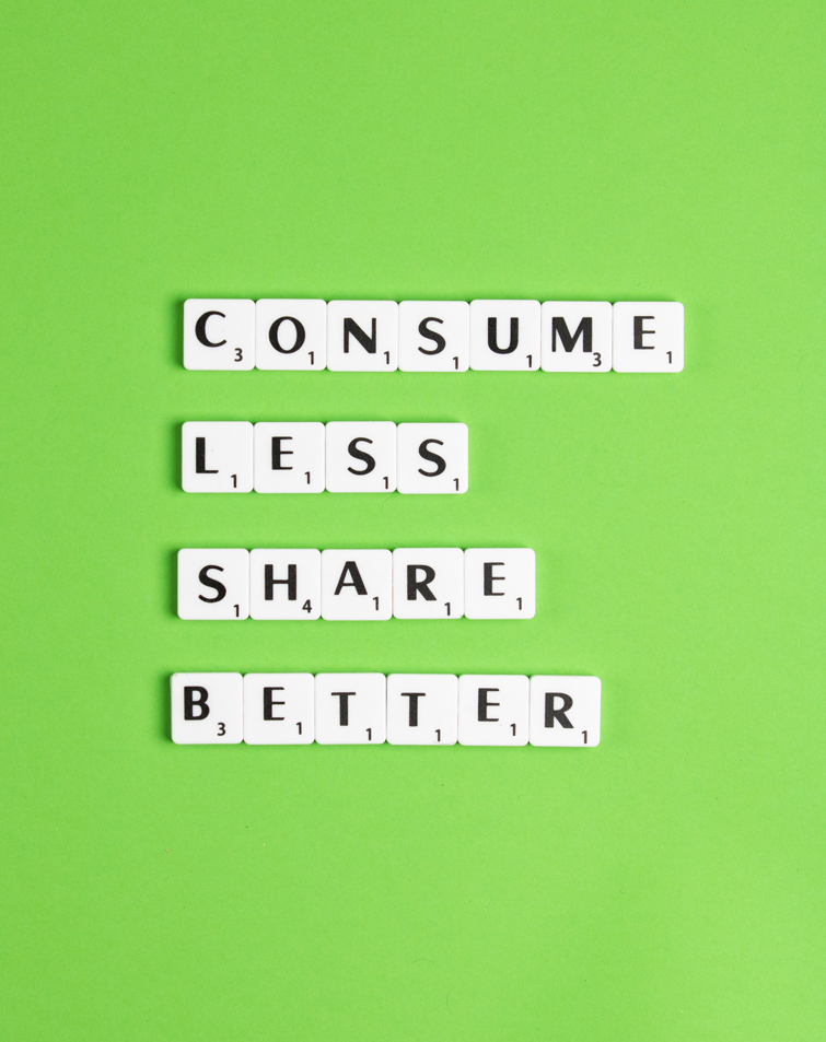 was ist kreislaufwirtschaft? Scrabble-Münzen auf einem grünen Hintergrund, wo es geschrieben steht “CONSUME LESS SHARE BETTER”